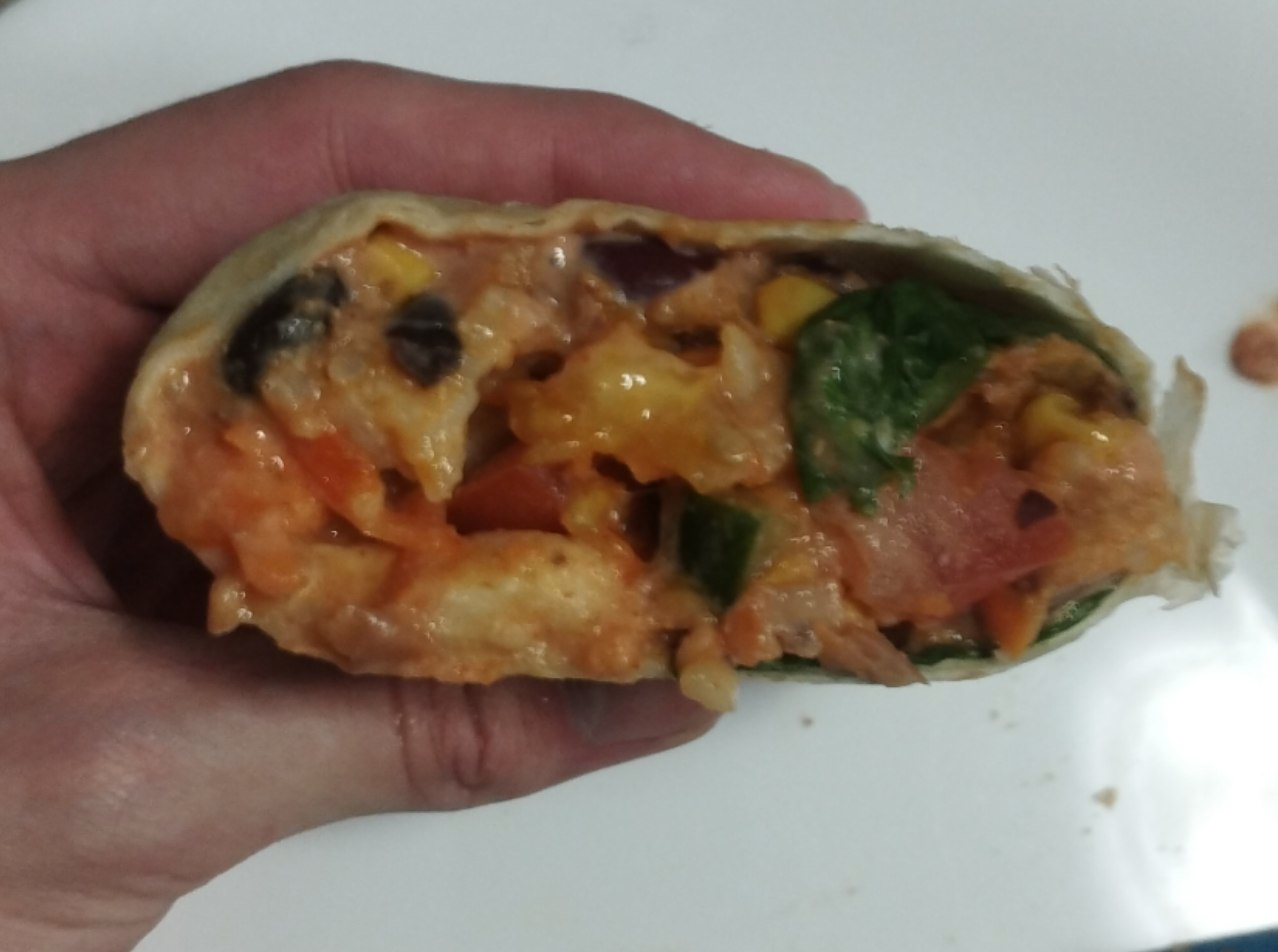 Spicy vegan wrap cut open in a hand